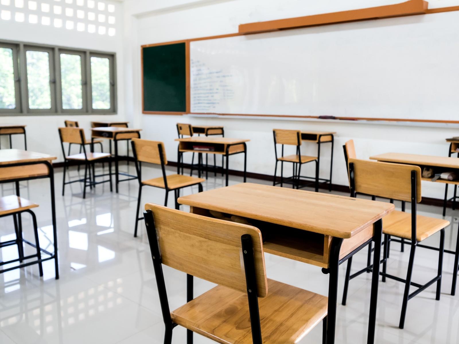 Leerer Klassenraum mit Tischen und Stühlen aus Holz und einer Tafel