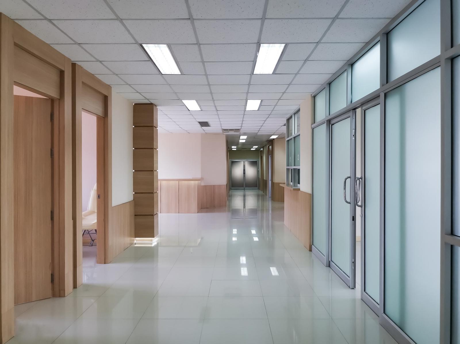 Heller, leerer Flur in einer Klinik mit Glastüren und Deckenleuchten