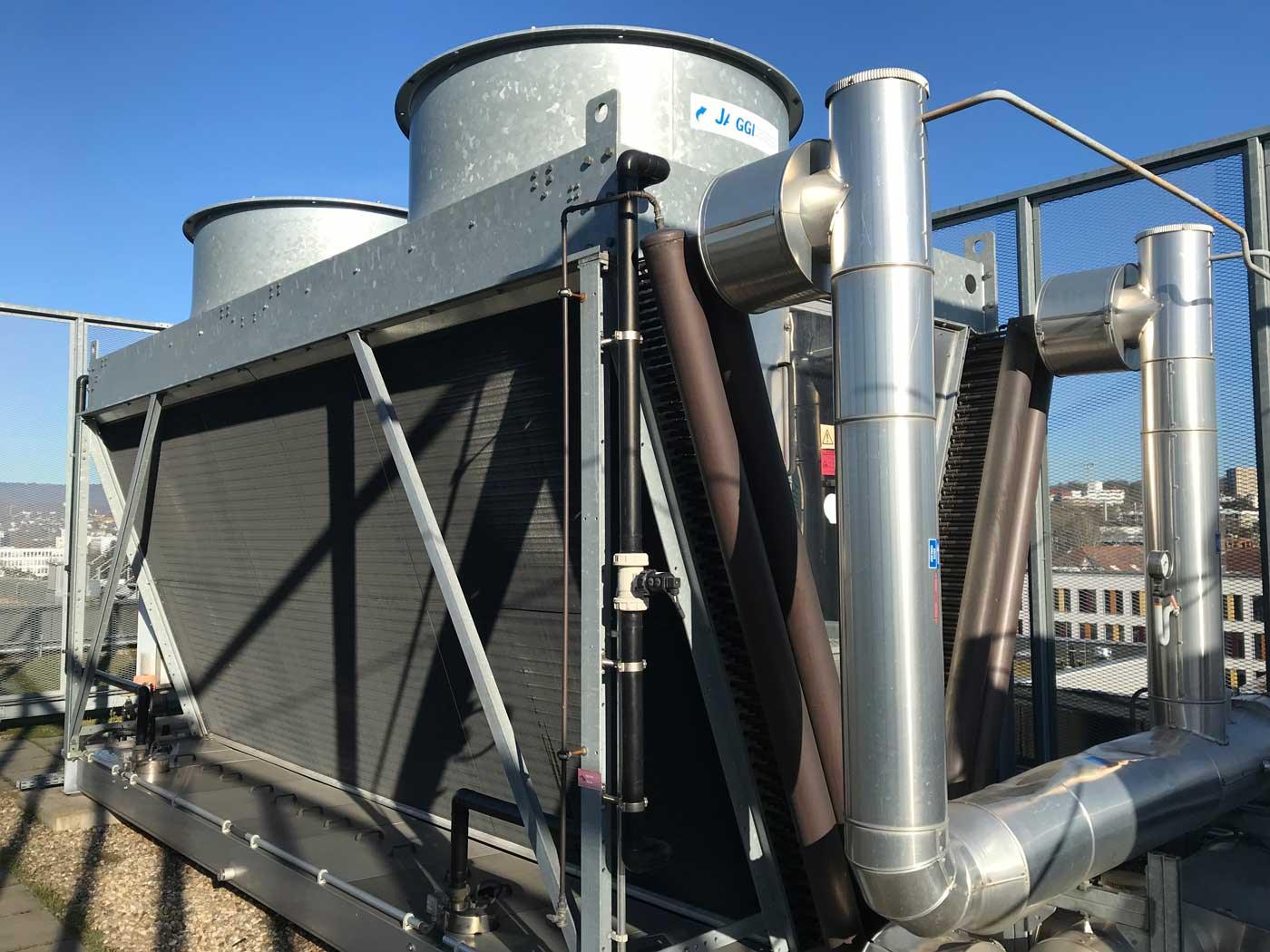 Rückkühlwerk mit zwei Ventilatoren und isolierten Rohrleitungen auf einem Flachdach